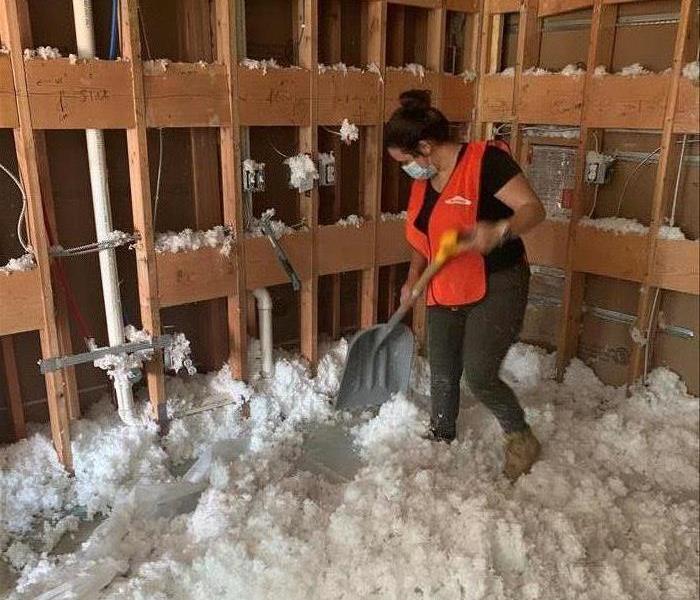 A worker scooping up insulation after a storm